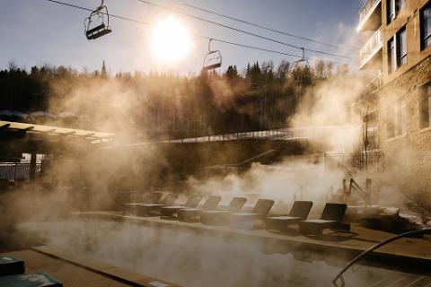Patchy fog surrounding the base of the ski lift on a sunny winter day.
