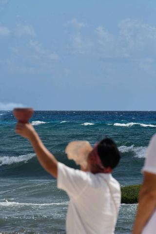 A man bowing through a sea shell on the beach