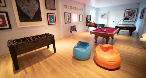A bright kids play room with arcade games, a foosball table and two bean bag chairs among other amenities