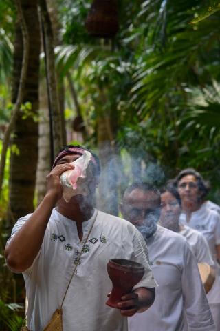 man blowing smoke through conche shell