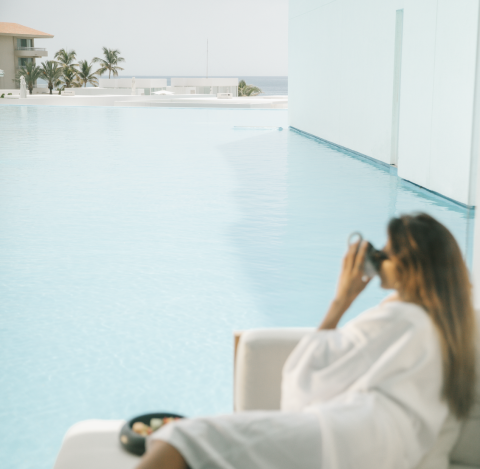 A guest enjoying a serene moment by a lagoon-style pool at the Viceroy Los Cabos resort