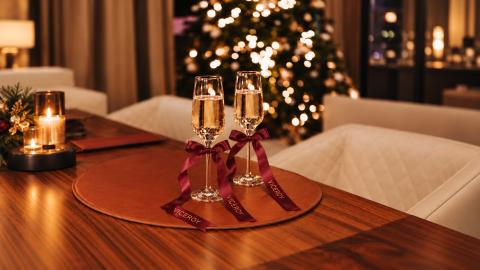 Two glasses of champagne on a table in a room full of Christmas decor