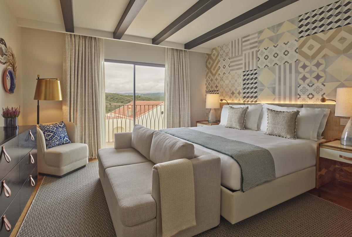 Bedroom with sofa at the foot of the bed and a small chair