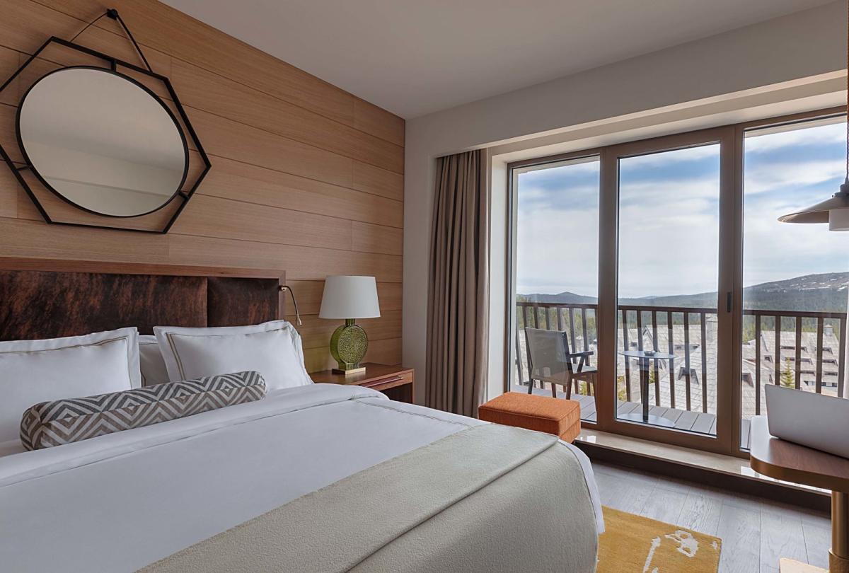 A king bed and a balcony in a suite at Viceroy Kopaonik Serbia