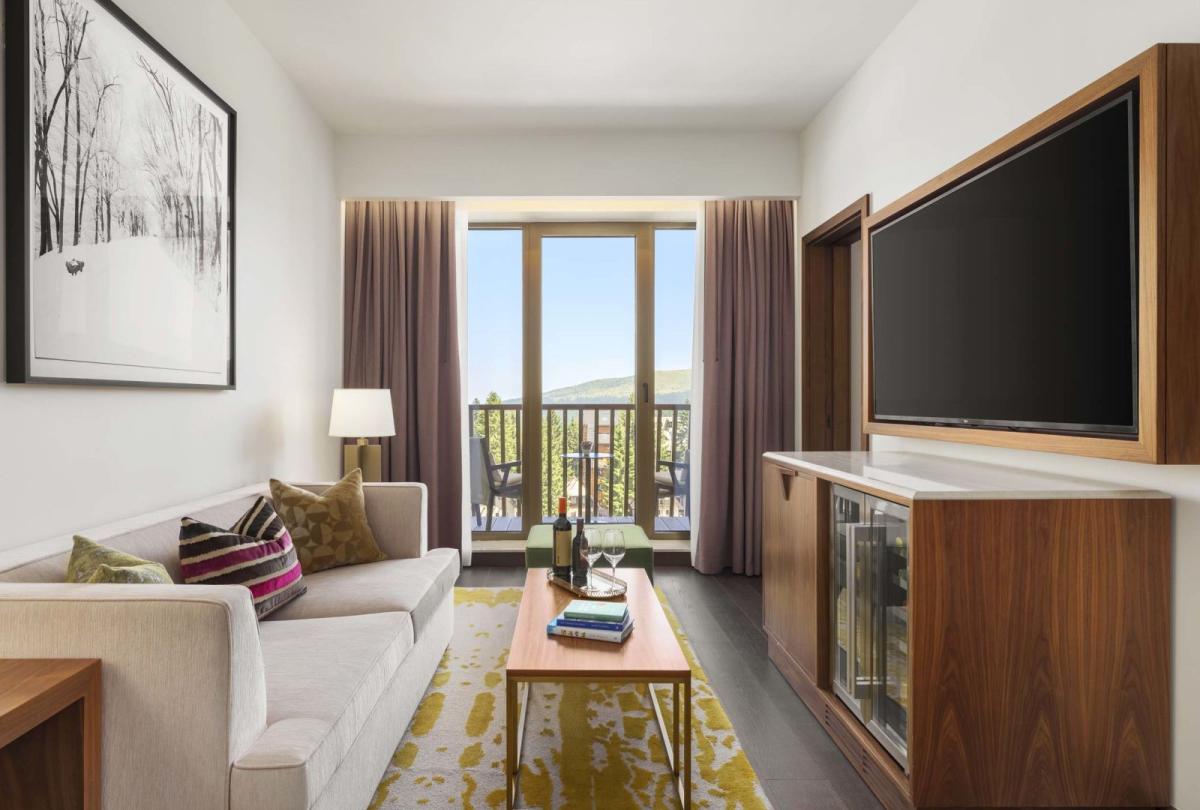 The living space with a couch, credenza, tv, and balcony in a suite at Viceroy Kopaonik Serbia