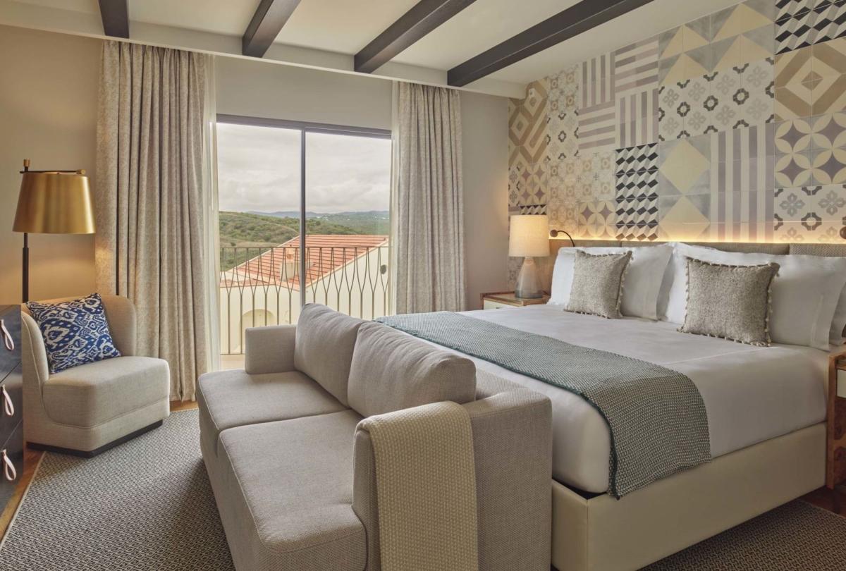 A bed with a couch and a chair in a one bedroom suite at Viceroy Ombria Algarve