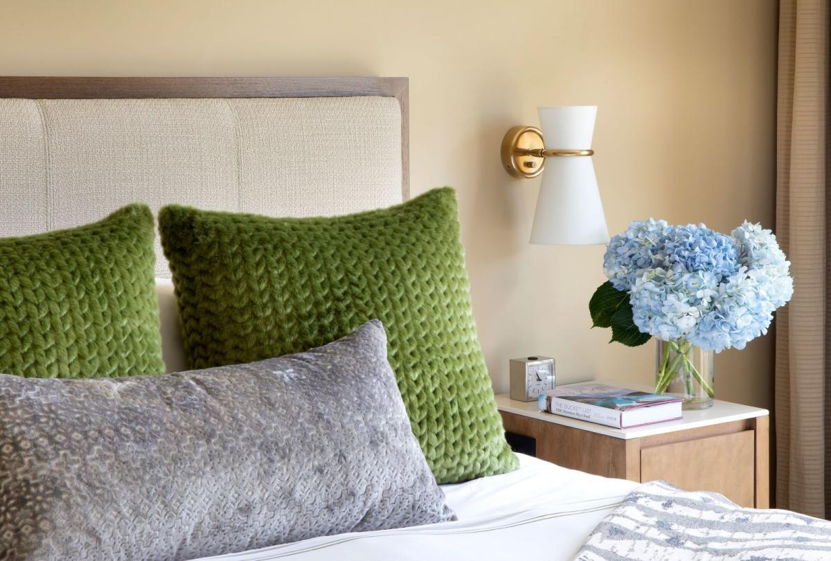 A king bed with green pillows on it and blue flowers on the nightstand in a pinnacle two bedroom residence at Viceroy Snowmass