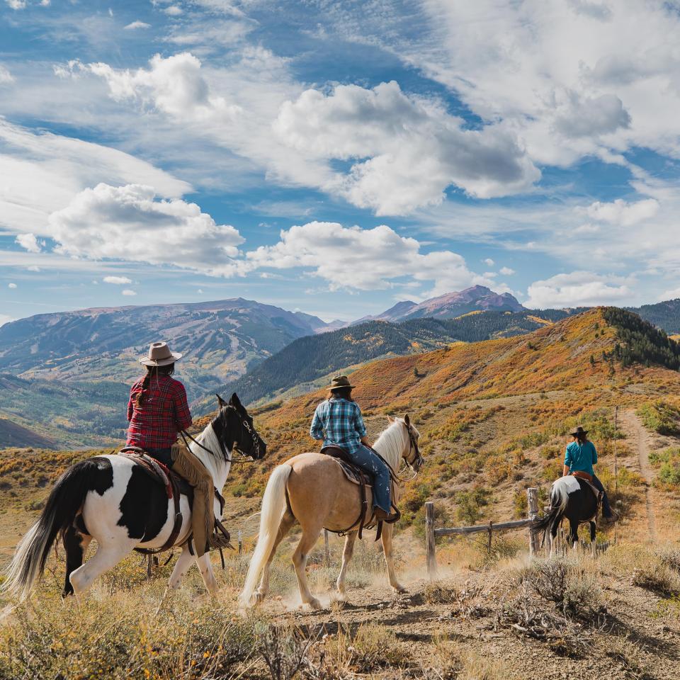 group of people on horseback ride through mountainous trails