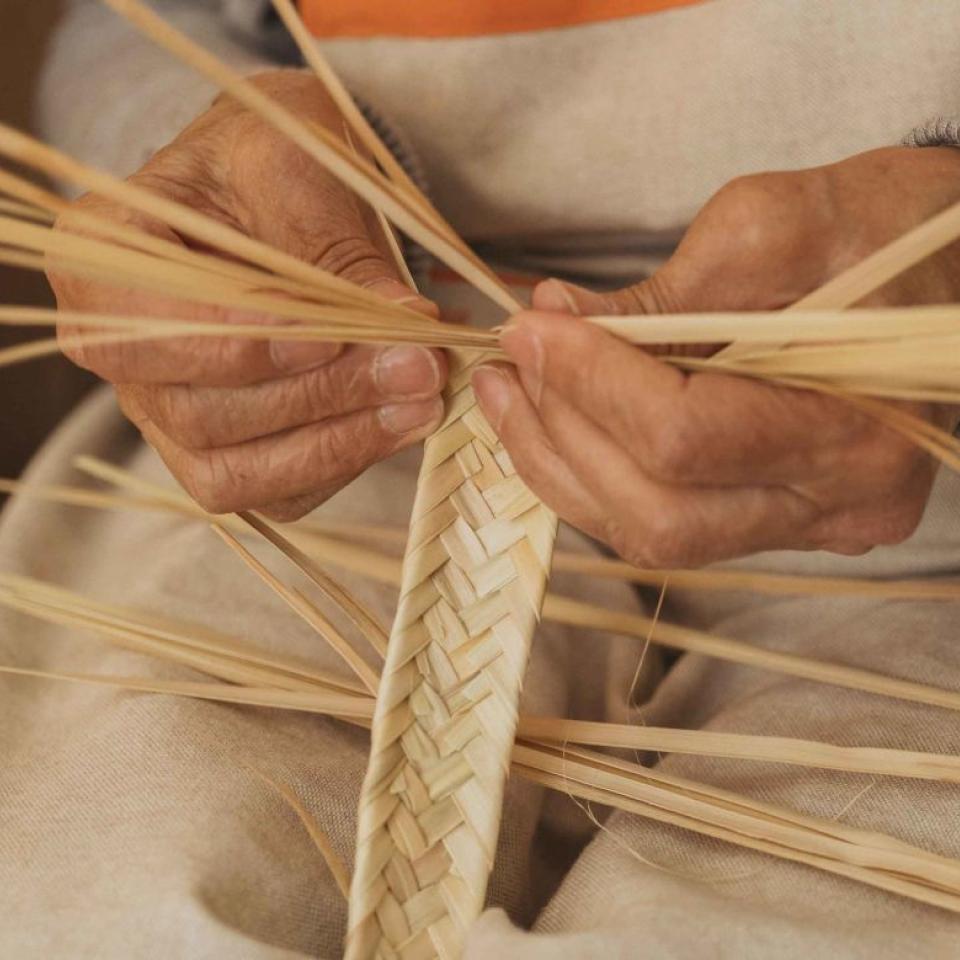 Detail of hands weaving the handle of a basket