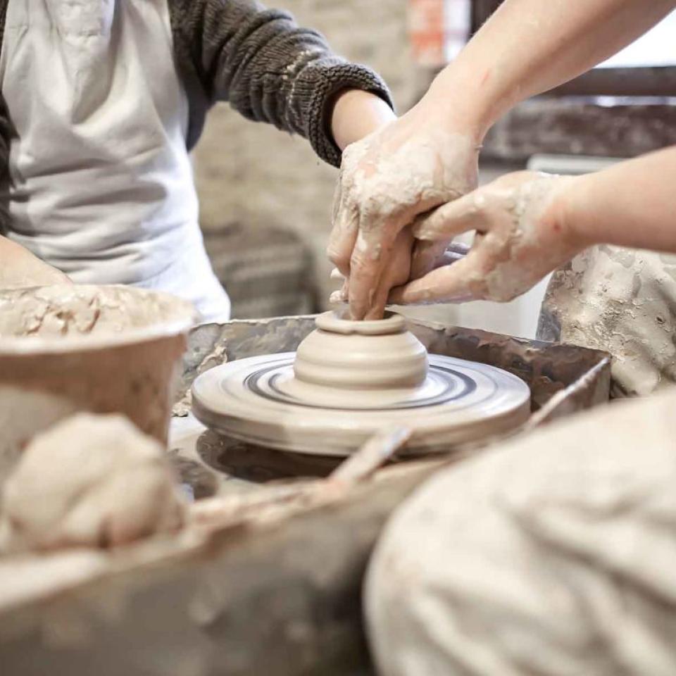 Two potters working on a pottery wheel