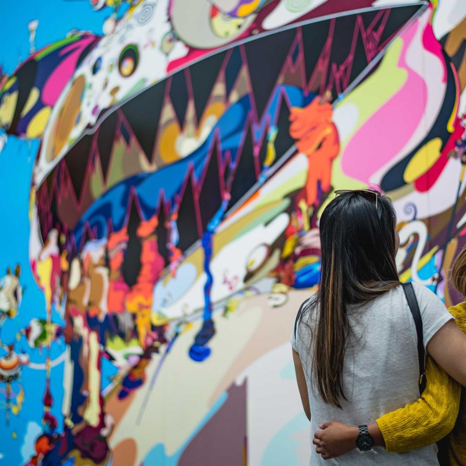 Two visitors to Chicago, arm in arm, appreciate a large street art mural