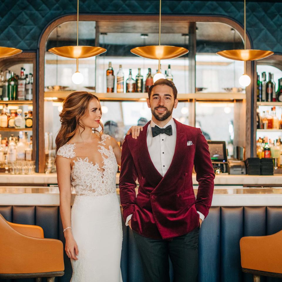 A bride and groom posing in front of a bar top