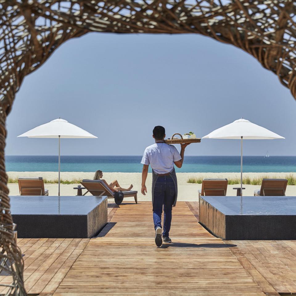 A server brings drinks to the beach-side bar Nidito, a paddock adjacent to Nido restaurant