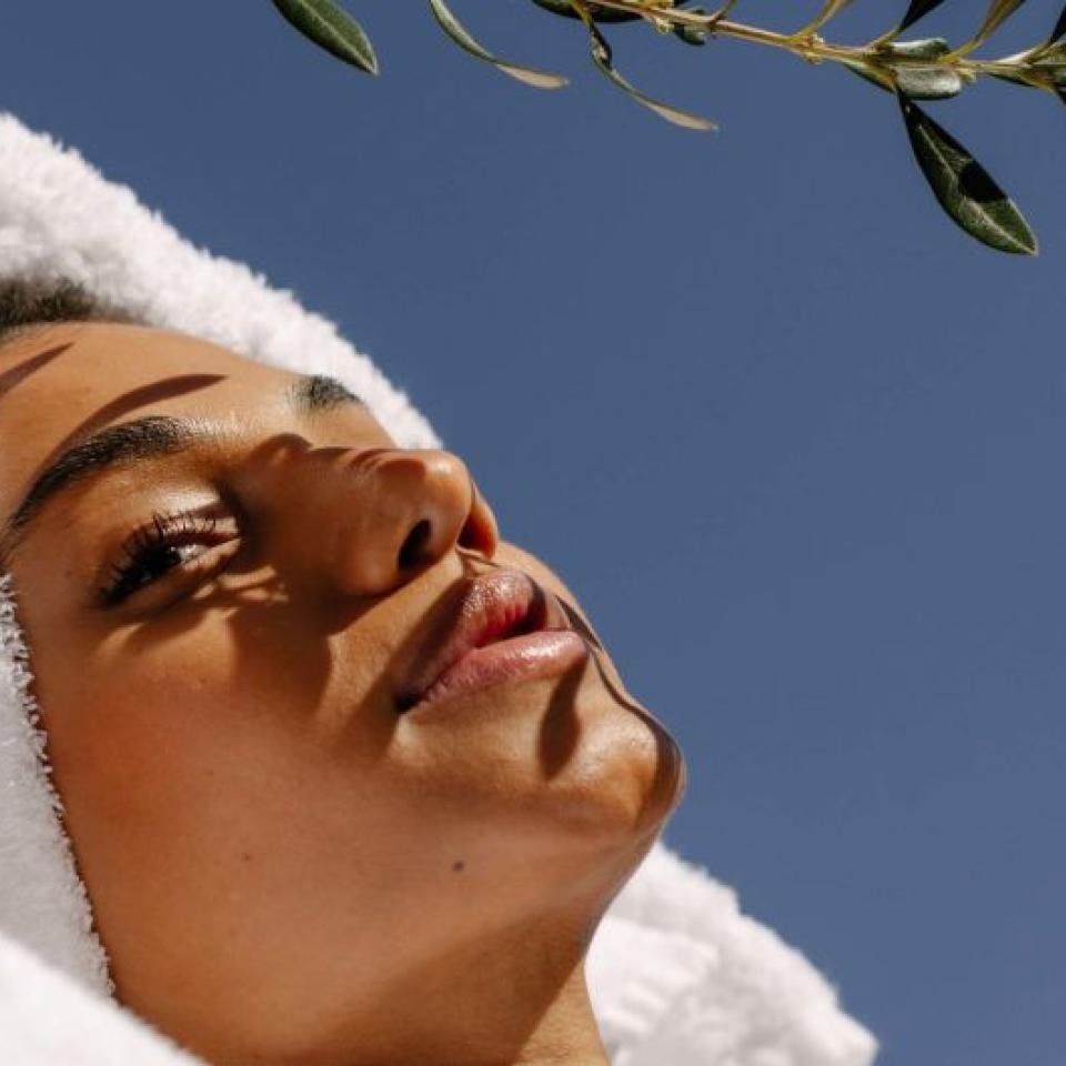 A person wearing a towel wrapped around their head relaxes under a tree