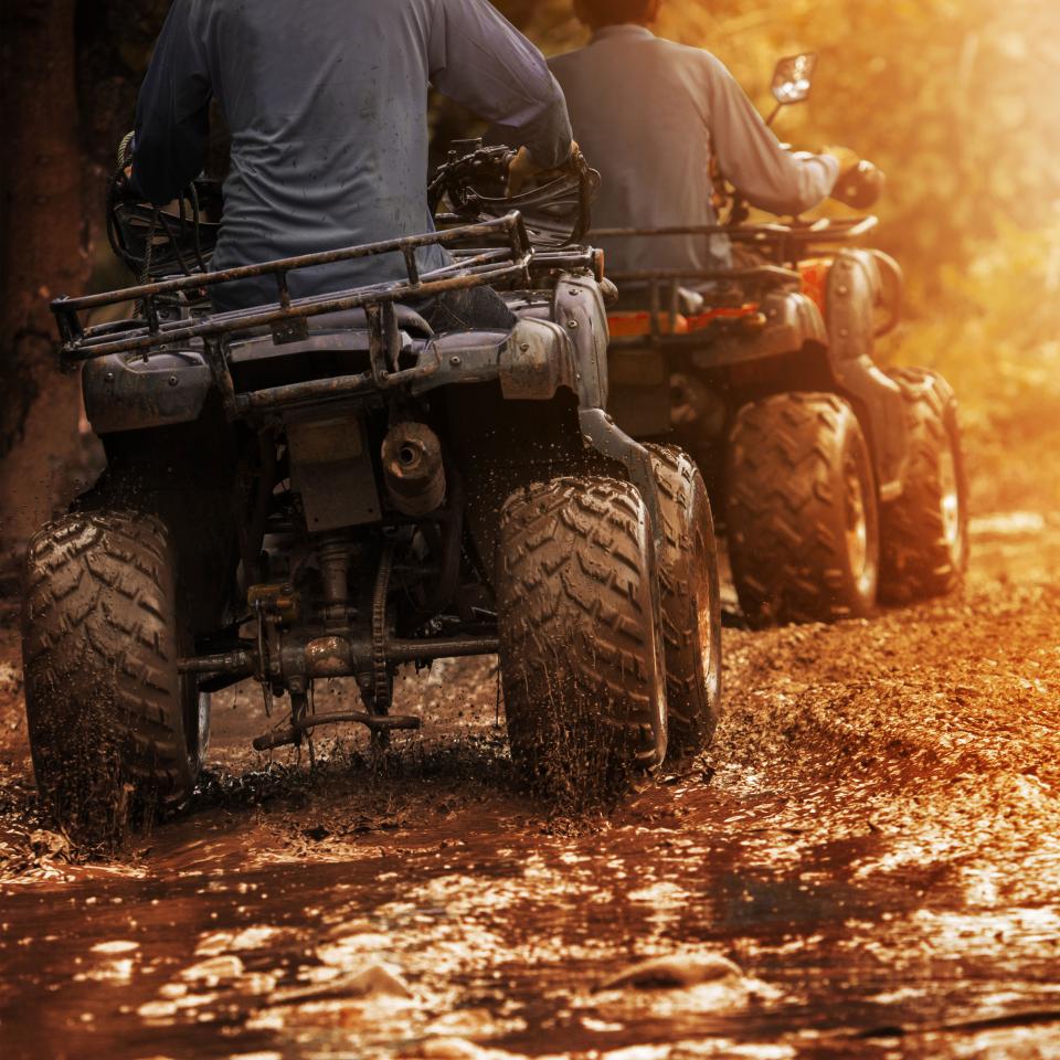 All terrain vehicles driving down a muddy path