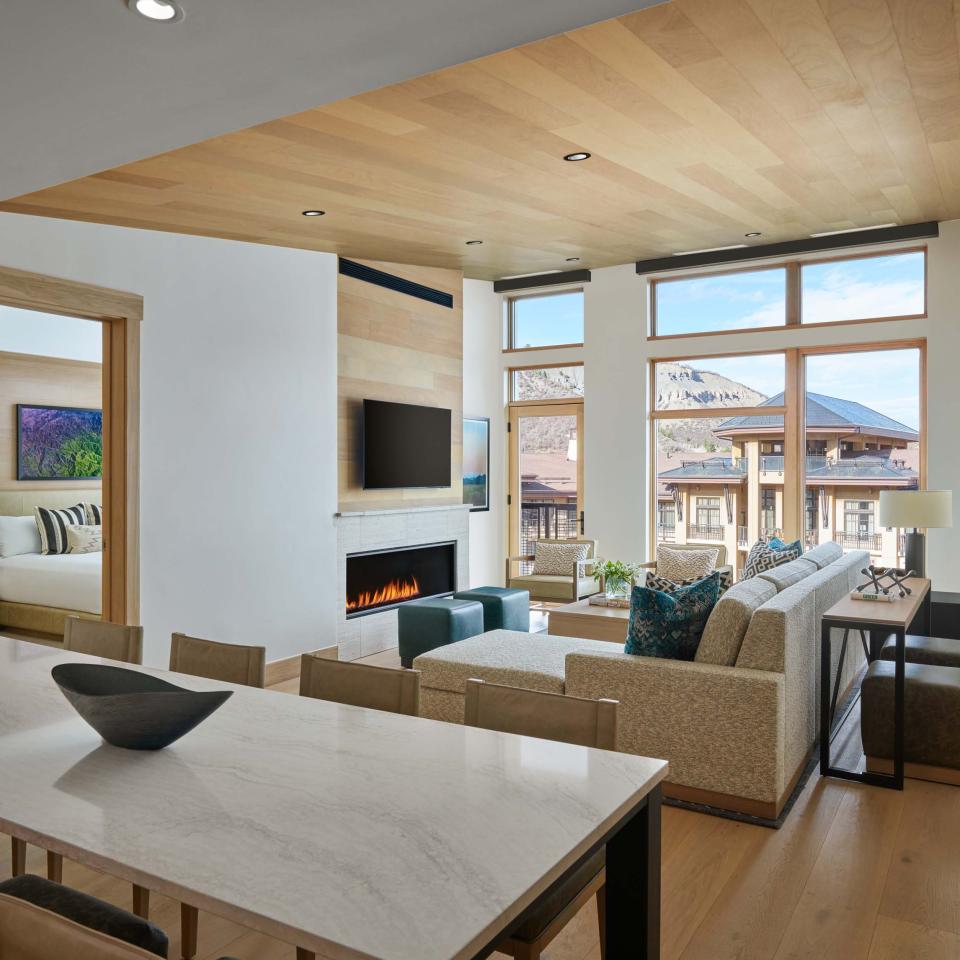 A Snowmass suite living room, with a wall mounted TV and a view of the mountains from a large bright window