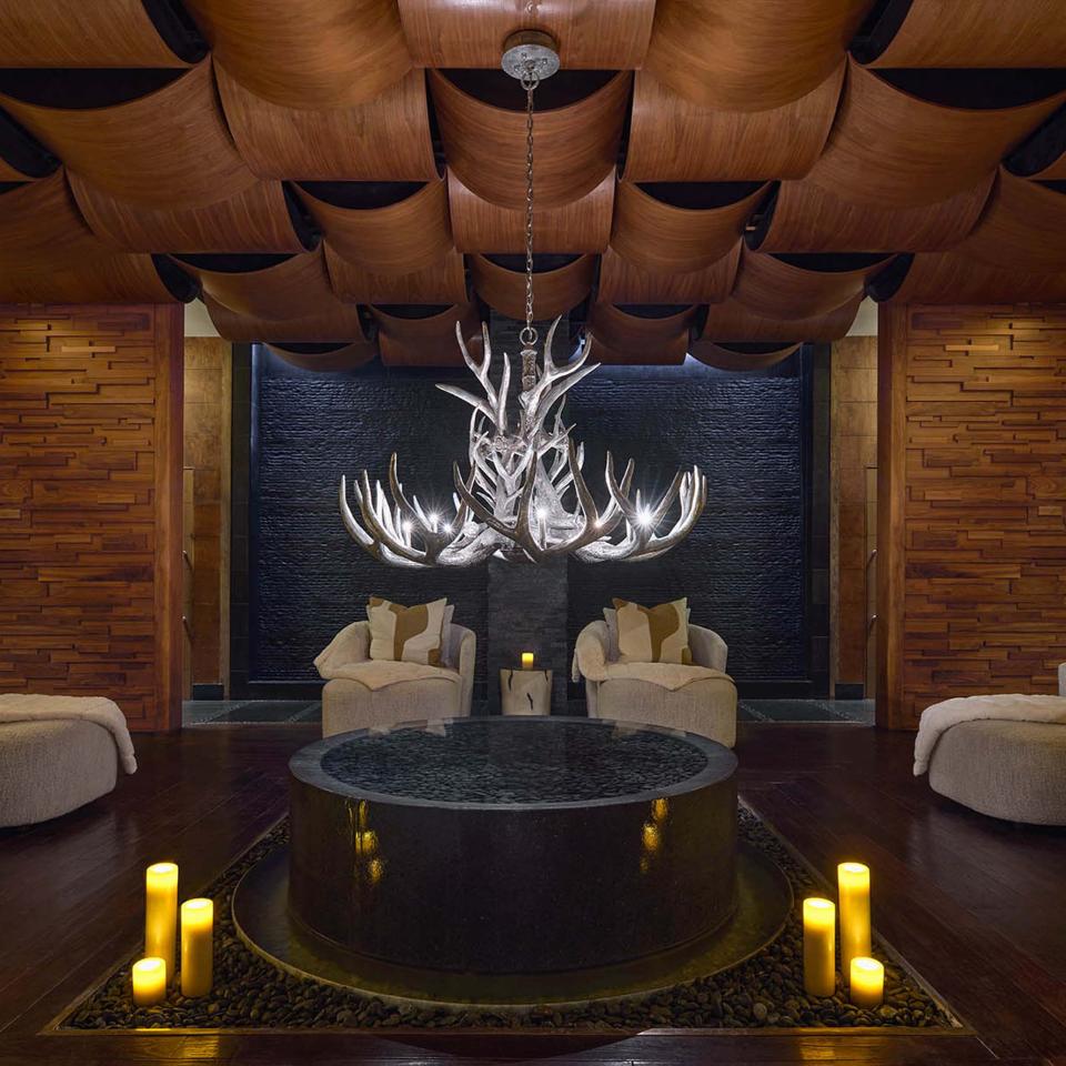 A Viceroy Snowmass spa waiting room, featuring cozy chairs and plush curtains, lit by candle