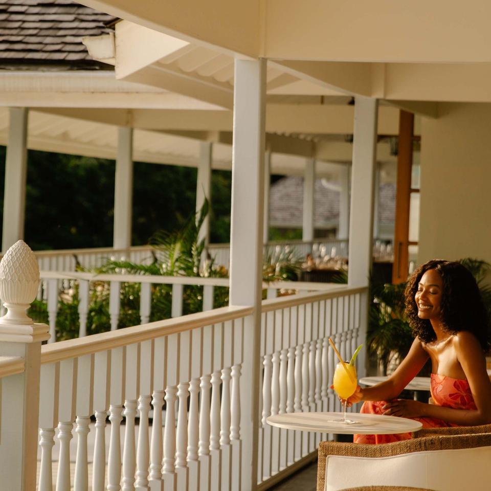 A woman drinking a tropical drink on a balcony