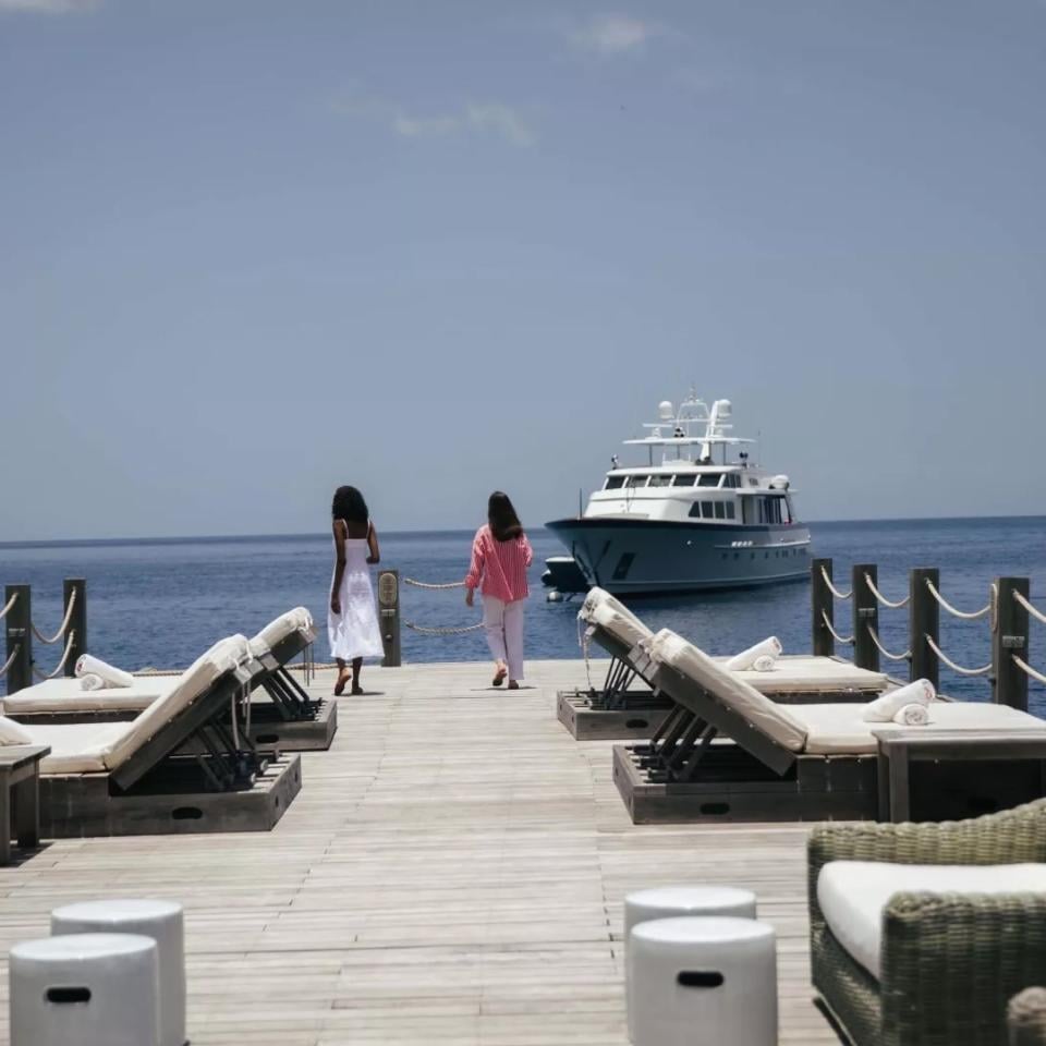 A man and woman walk on a dock at Sugar Beach as a Yacht comes to port