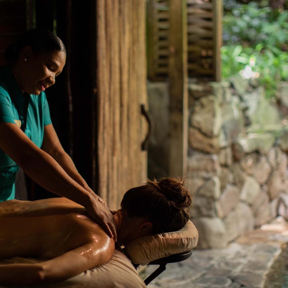 a woman receives a massage in a cabana next to a tranquility pool