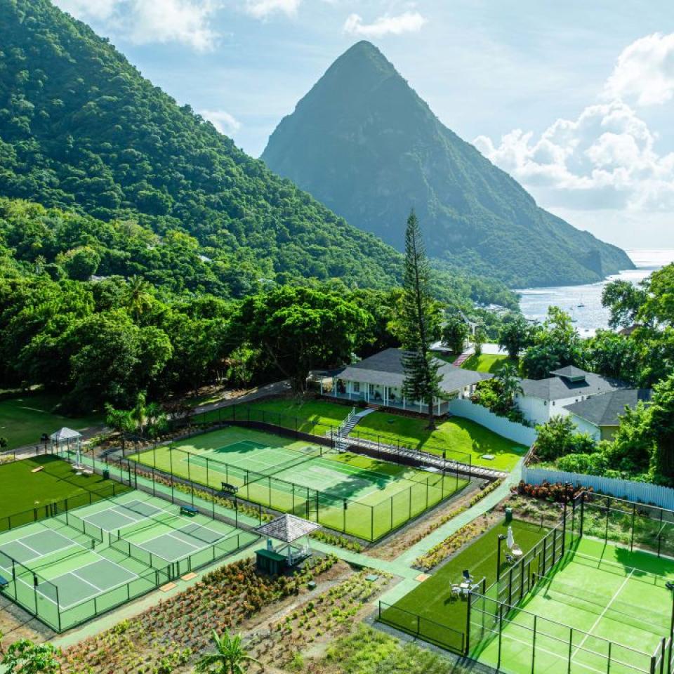Grass tennis courts nestled amongst tropical trees at the base of the Pitons at Sugar Beach