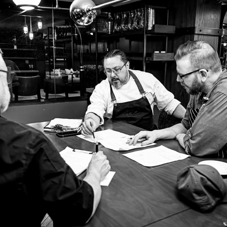 Dovetail Executive Chef James Gee, discussing the restaurant menu with associates