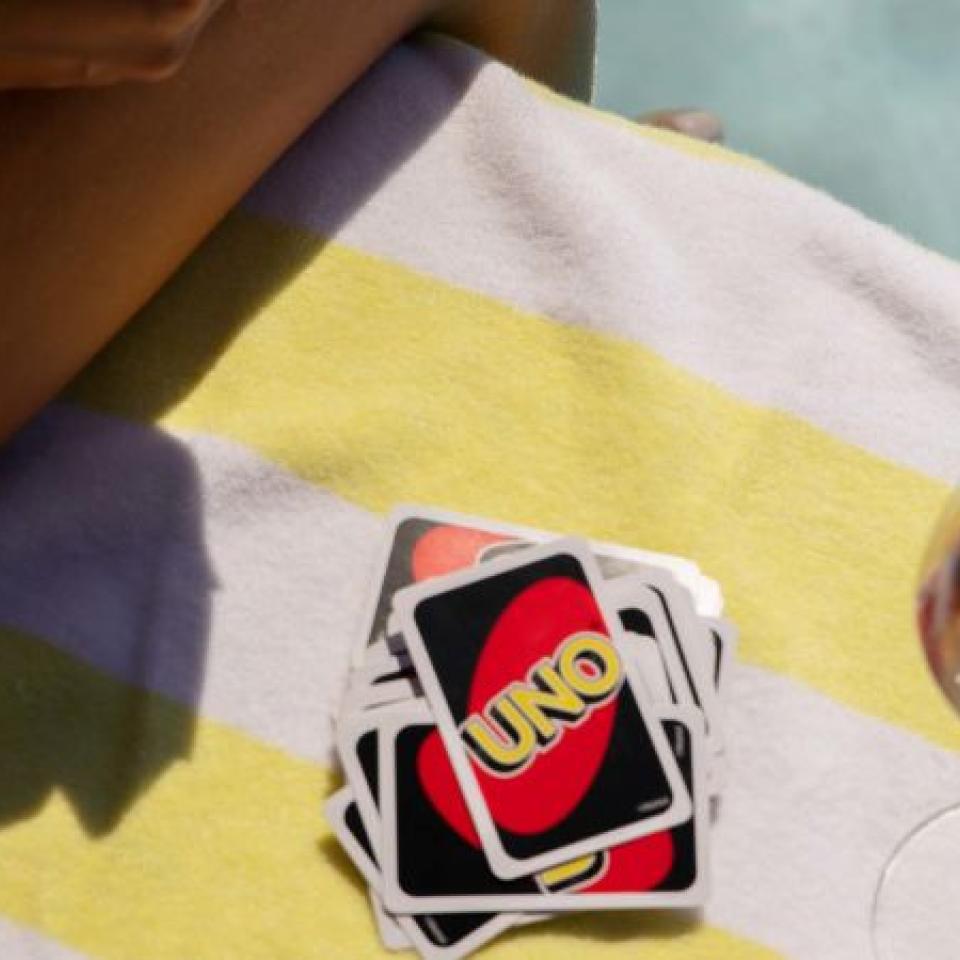 a stack of Uno cards on a towel, next to a glass of wine