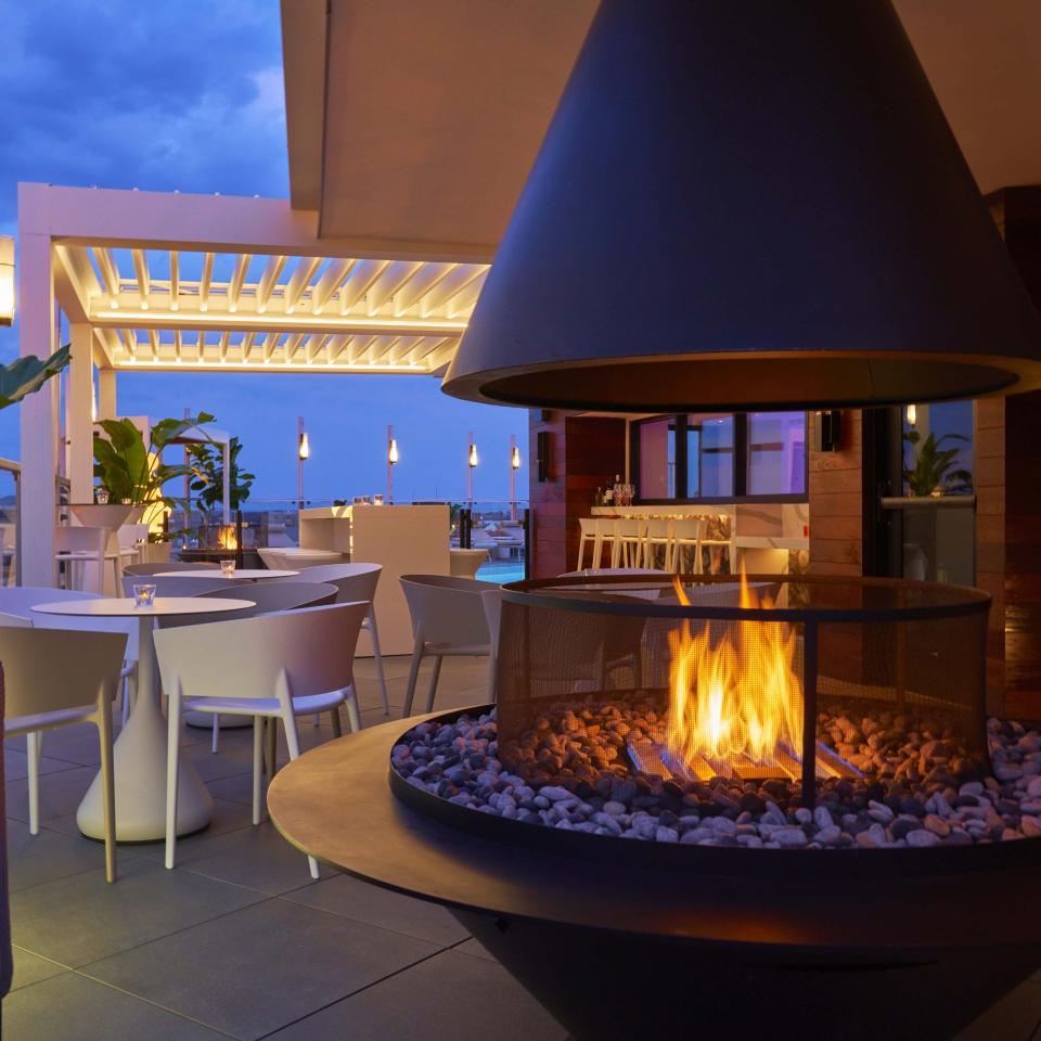 A restaurants patio with a large fire pit and lounge area at Viceroy Zena