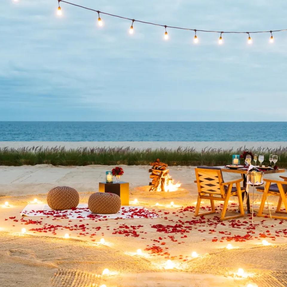 A candle lit walk way on the beach to a private table for the private beach dining event