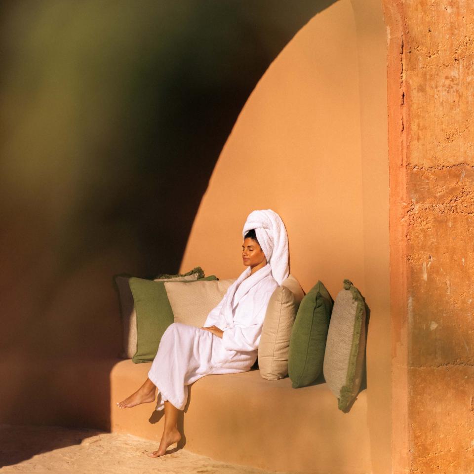 Una mujer está sentada al sol a la entrada de un spa