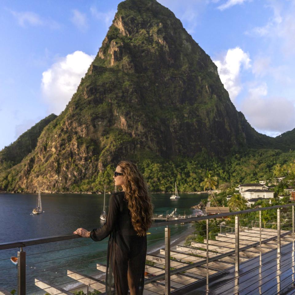 A woman standing on a balcony looking at the ocean at Spice of Life Residence