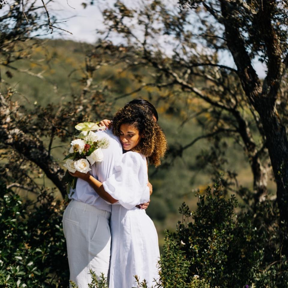 A couple embrace at their wedding surrounded by nature.