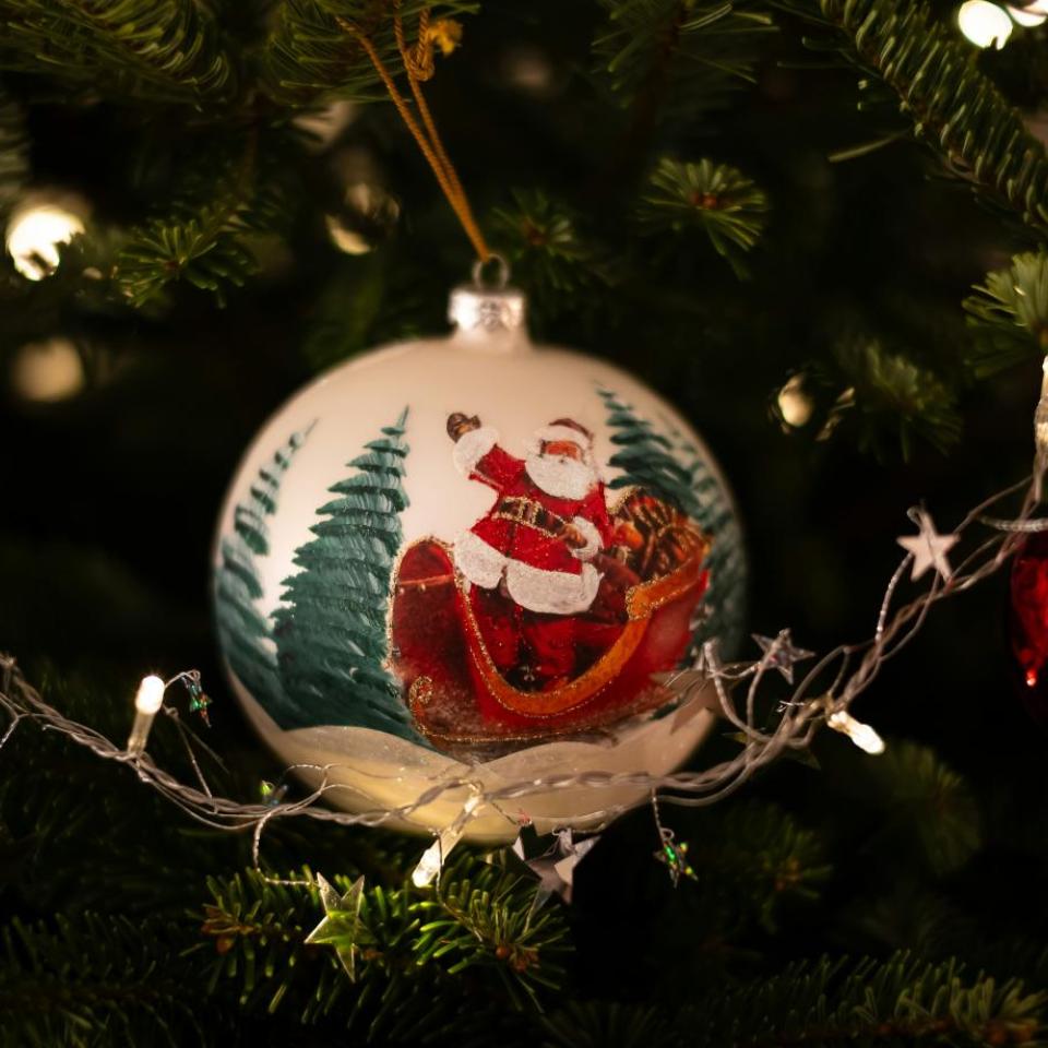 A Santa Claus ornament hangs on a Christmas Tree