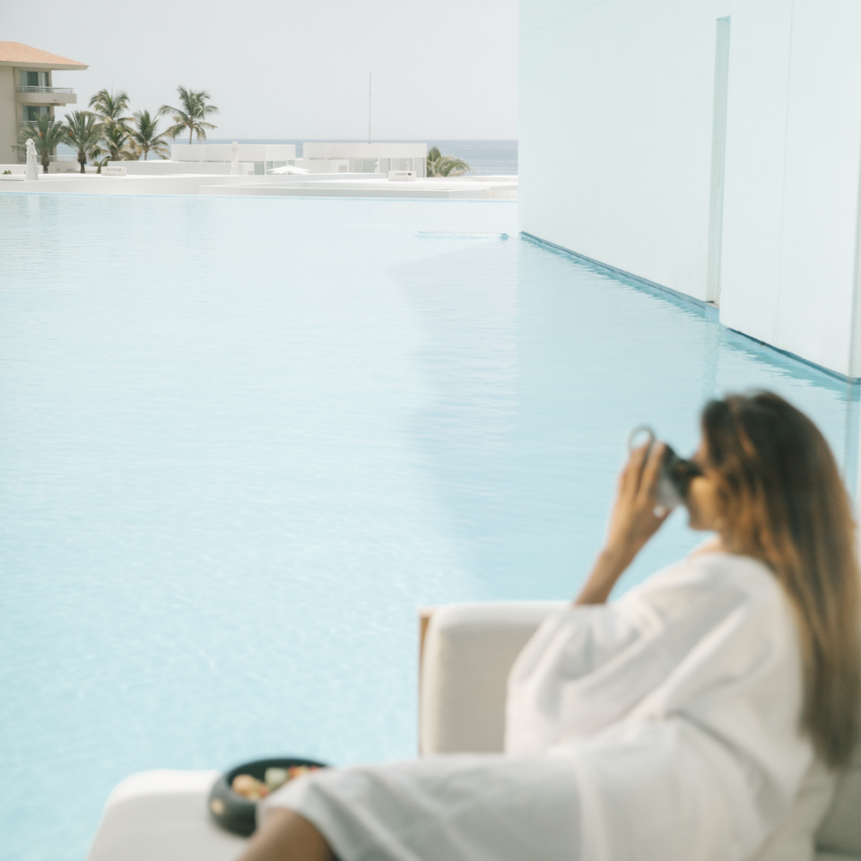 A guest enjoying a serene moment by a lagoon-style pool at the Viceroy Los Cabos resort