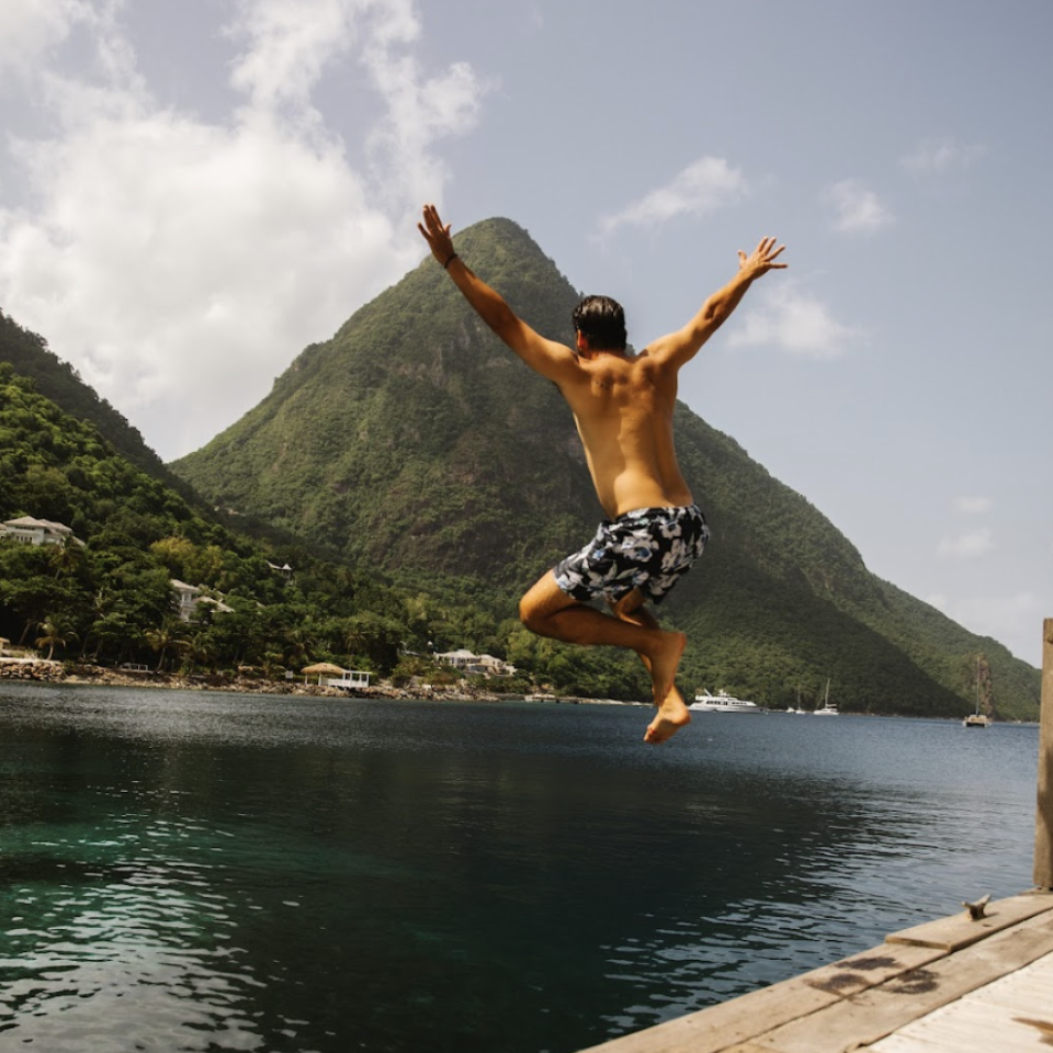 guest jumping off a dock into the water at Sugar Beach, A Viceroy Resort in St. Lucia. 