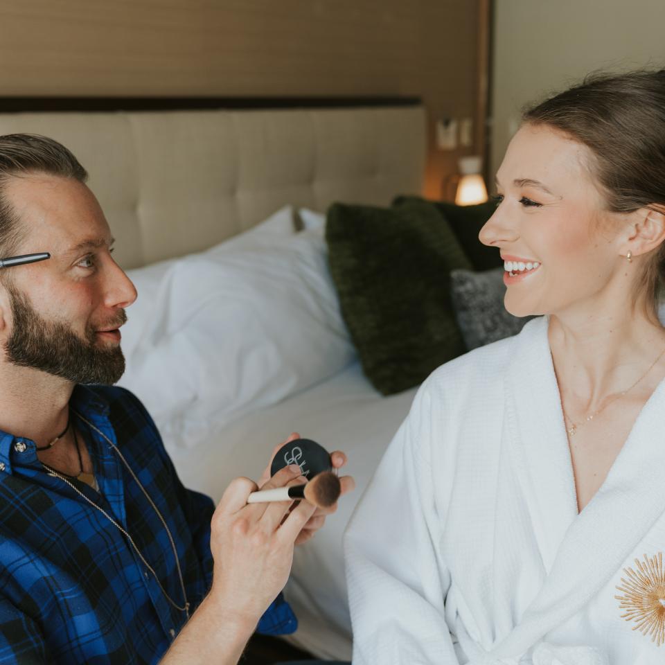 A makeup artist smiling at the bride