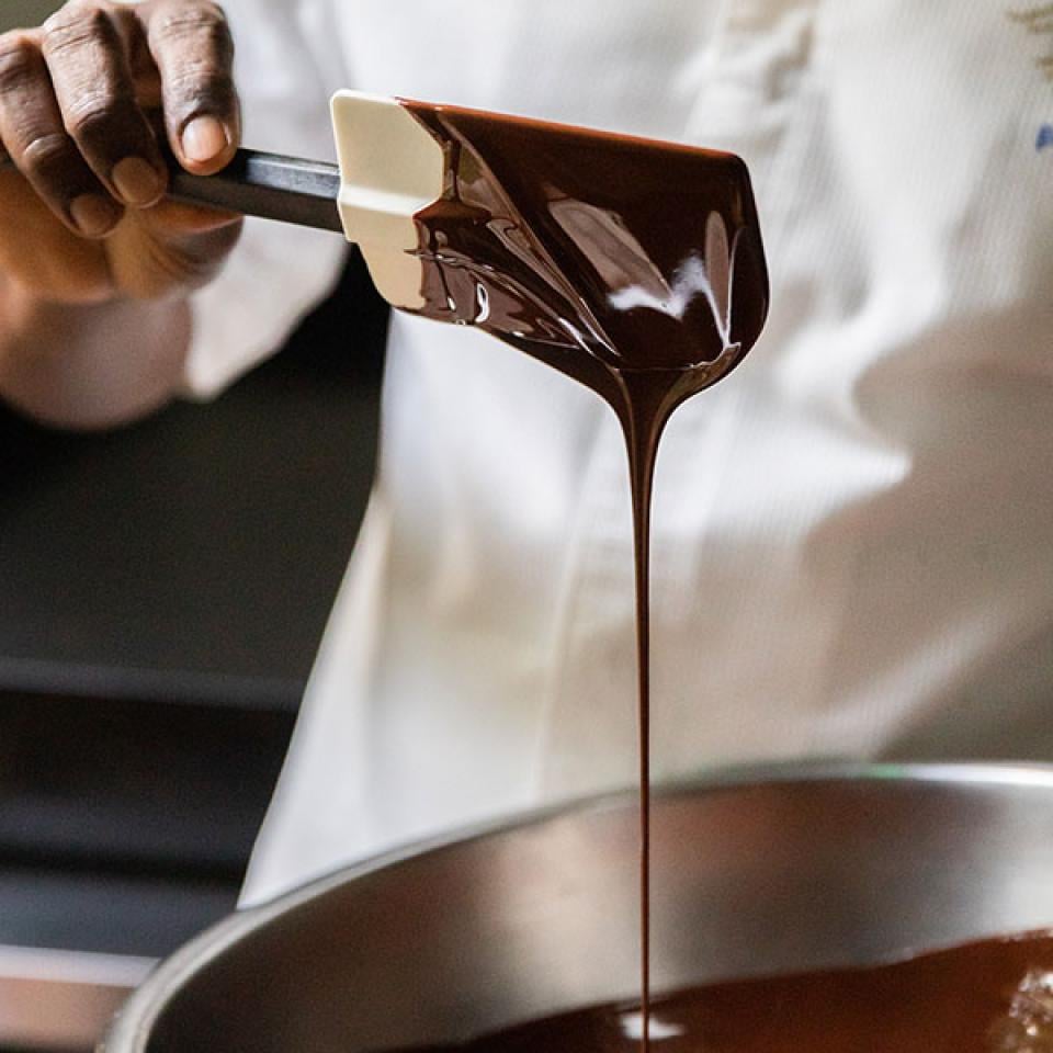 Un chef en train de mélanger du chocolat dans un saladier.