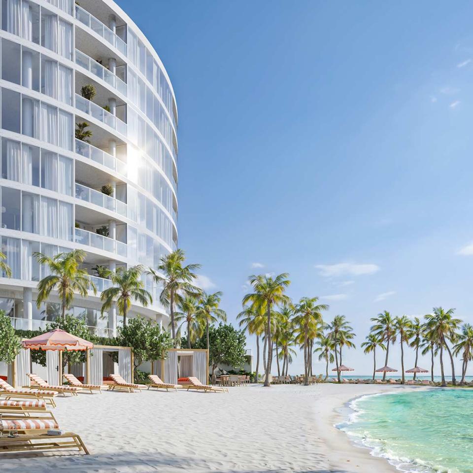 Un bâtiment moderne aux lignes courbes surplombe une plage de sable blanc immaculée, agrémentée de transats, de cabanes, de palmiers et d'une eau turquoise cristalline.