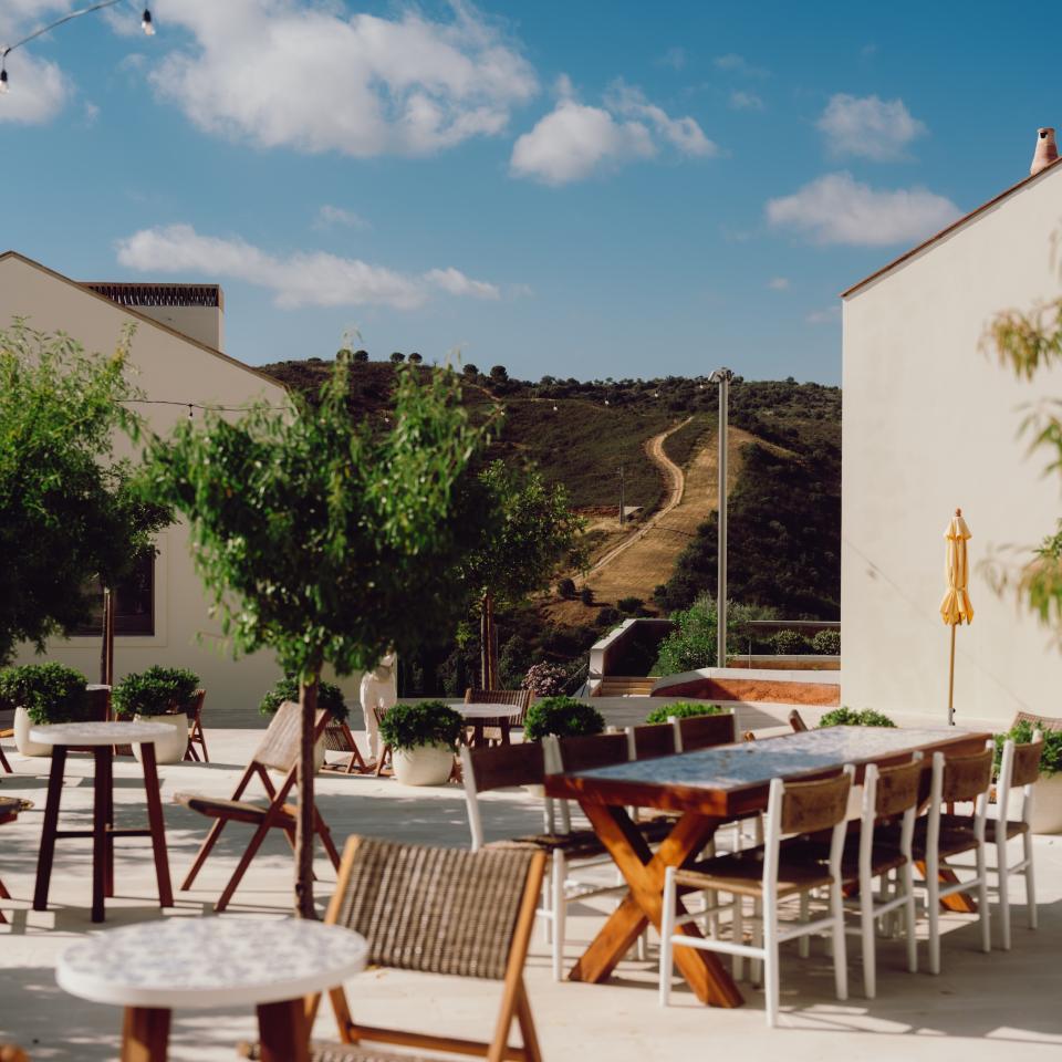 An outdoor terrace with dining tables and the Algarve countryside in the background