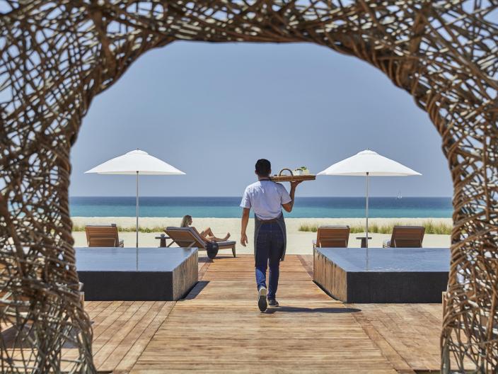 server walks with a tray on their shoulder toward the beach
