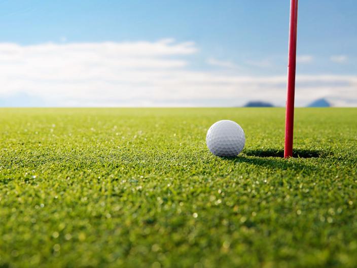 close up of golf ball on the green near the tee