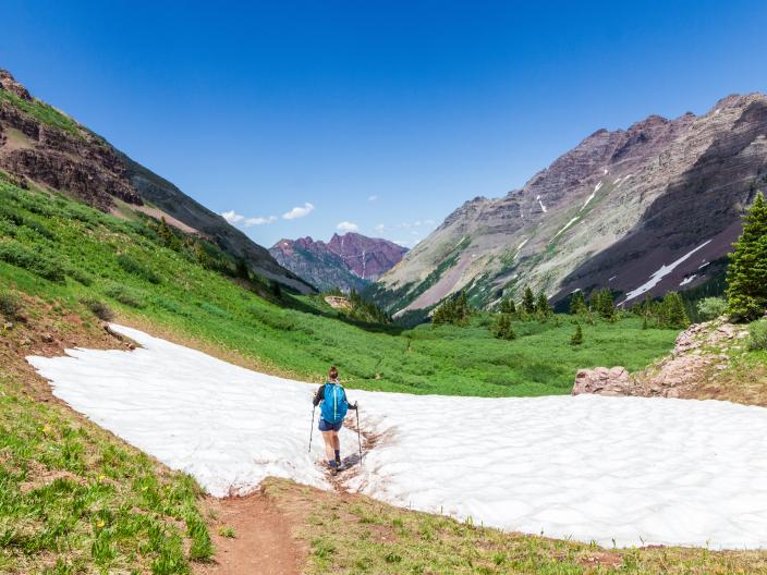 person hikes through snowy area with mountains in background
