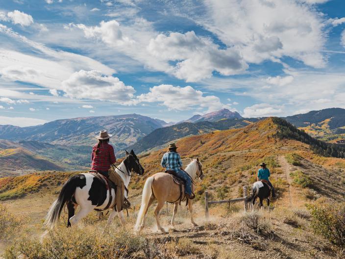 group of people on horseback ride through mountainous trails