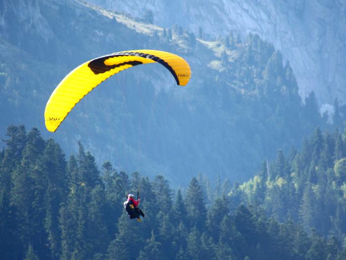 yellow paraglide parachuter with mountain range in background