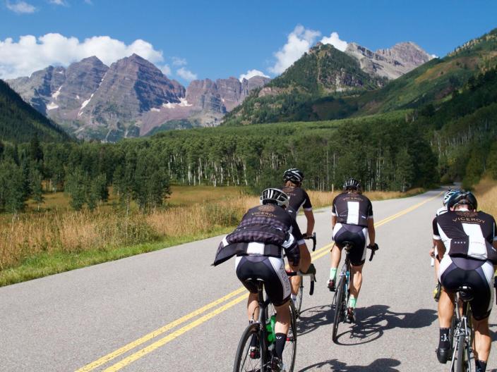 group of cyclers on paved road with mountains in background