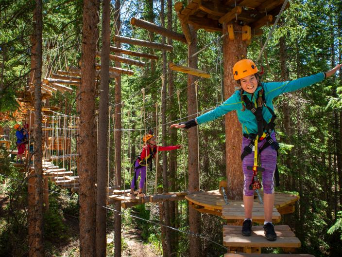 people in safety gear climb through platforms in trees