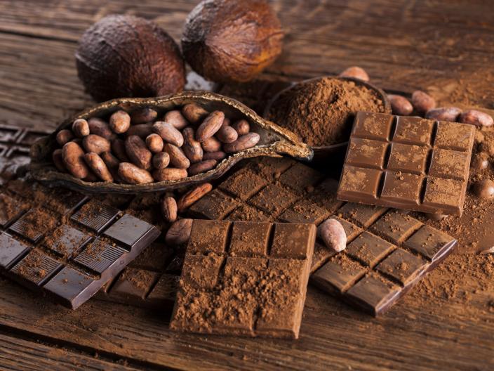 piles of cocoa beans and chocolate bars on wooden counter