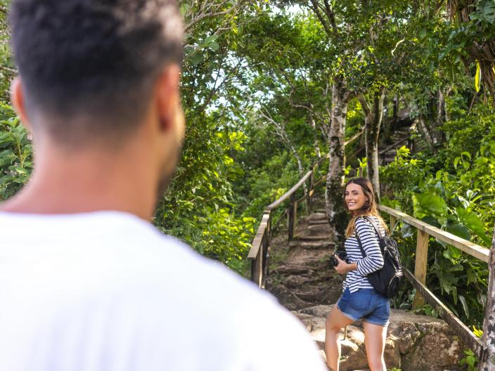 woman looks back at man while they hike through wooded area