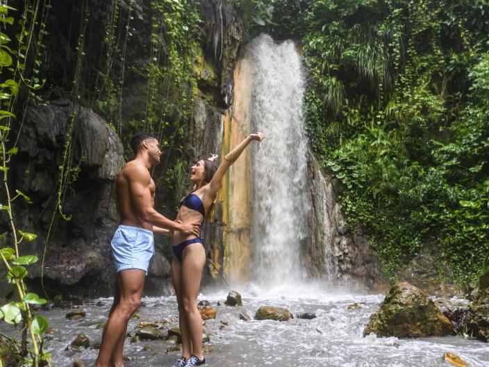 couple stand at the base of a waterfall