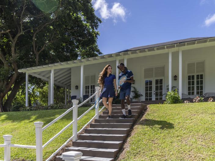 two people walk down stairs from a white building